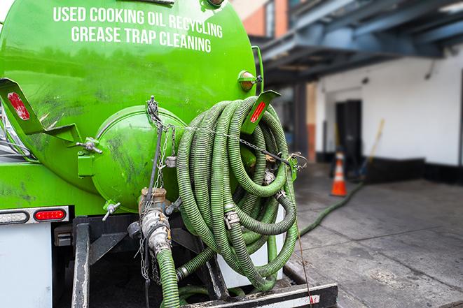 a technician pumping a grease trap in a commercial building in Costa Mesa